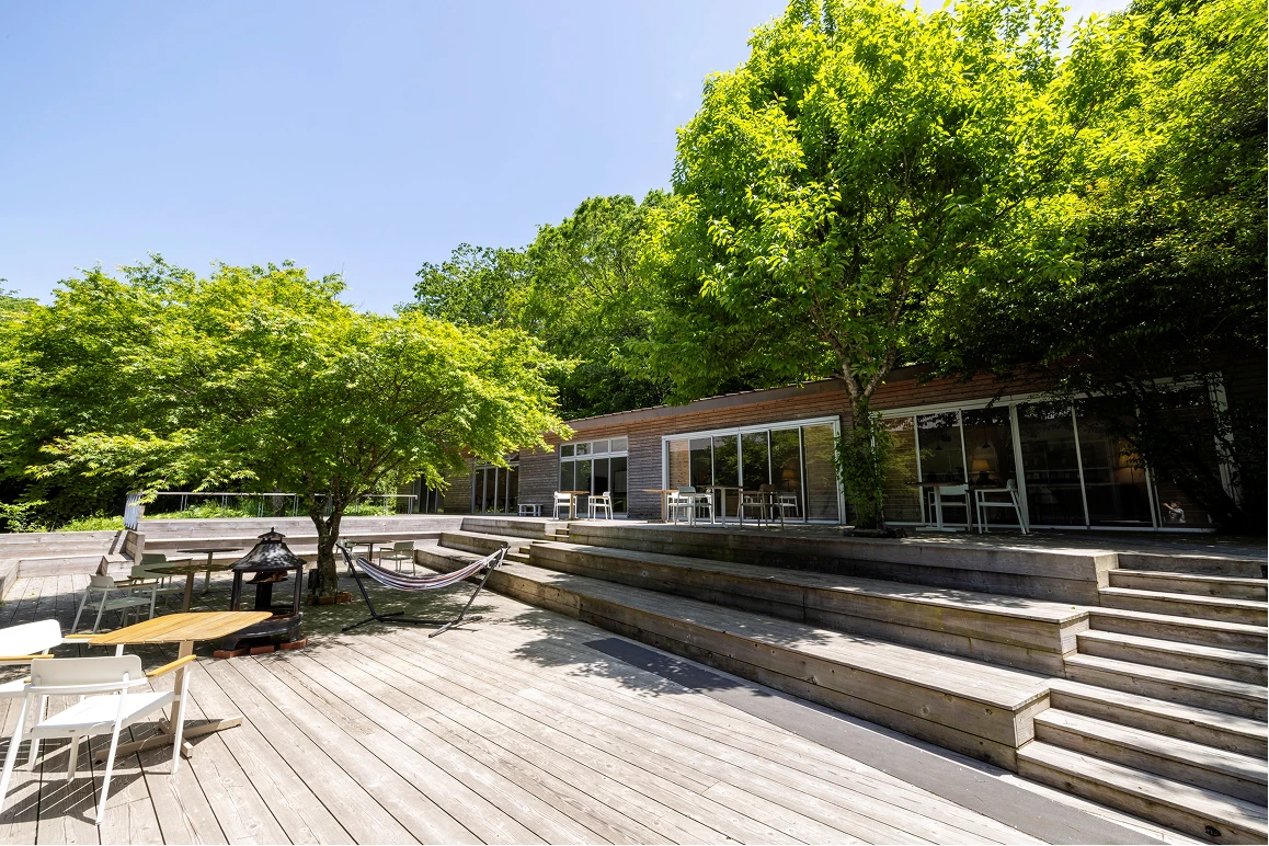 テラス席のある宿泊施設の外観、デッキに椅子とテーブルが並ぶ