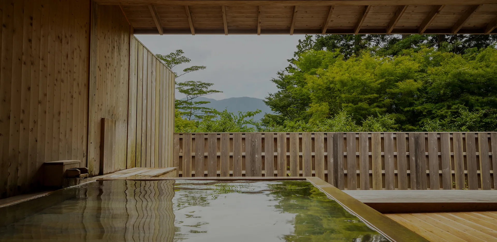 木の温もりに包まれた露天風呂、山並みと緑を眺めながら湯浴みできる空間